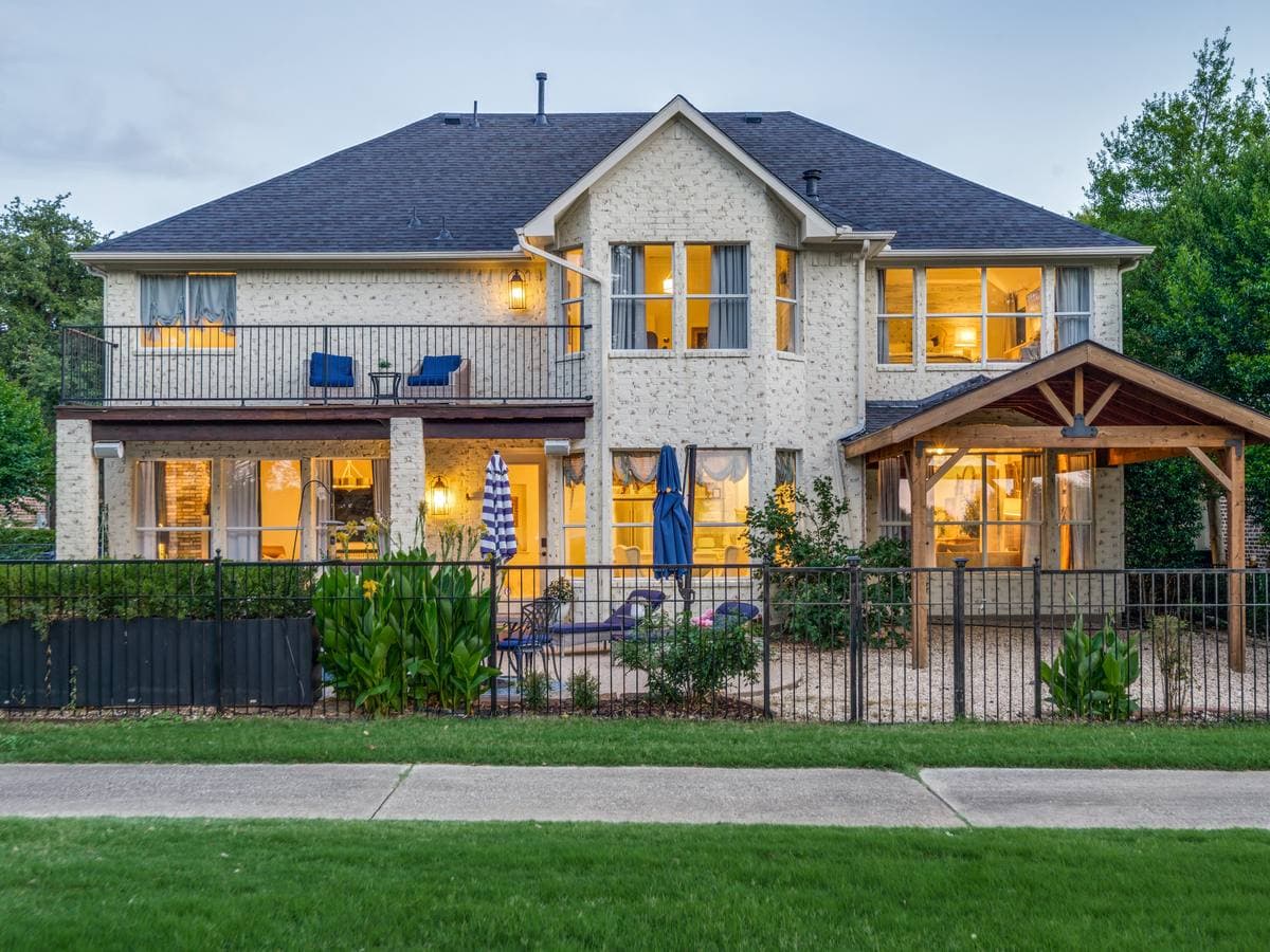 Warmly lit DFW home with covered patio and balcony at dusk — outdoor living ready for its next owner